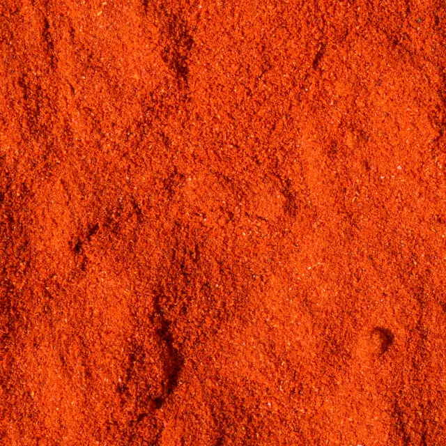 Imagine detaliată a boia de ardei premium, fin măcinată, arătând textura sa granulară și culoarea roșu aprins.